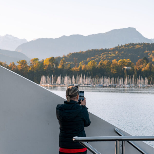 A tourist captures the serene beauty of a lake cruise in Lucerne, an experience to ponder when considering 'Is the Swiss Travel Pass worth it?'