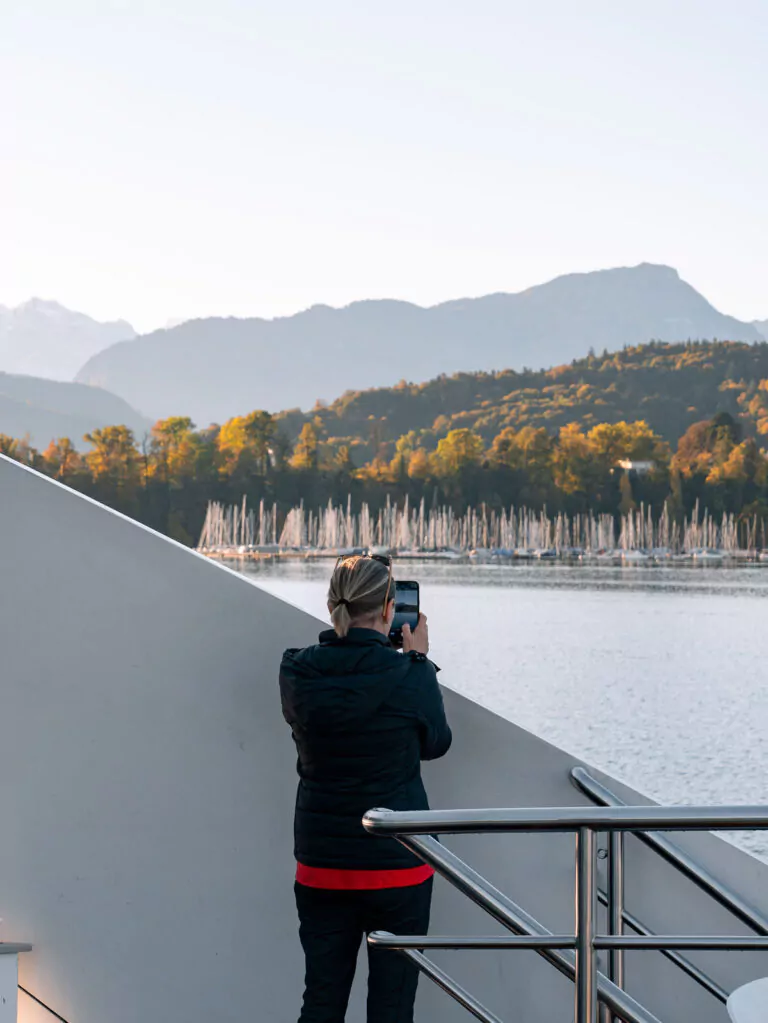 A tourist captures the serene beauty of a lake cruise in Lucerne, an experience to ponder when considering 'Is the Swiss Travel Pass worth it?'