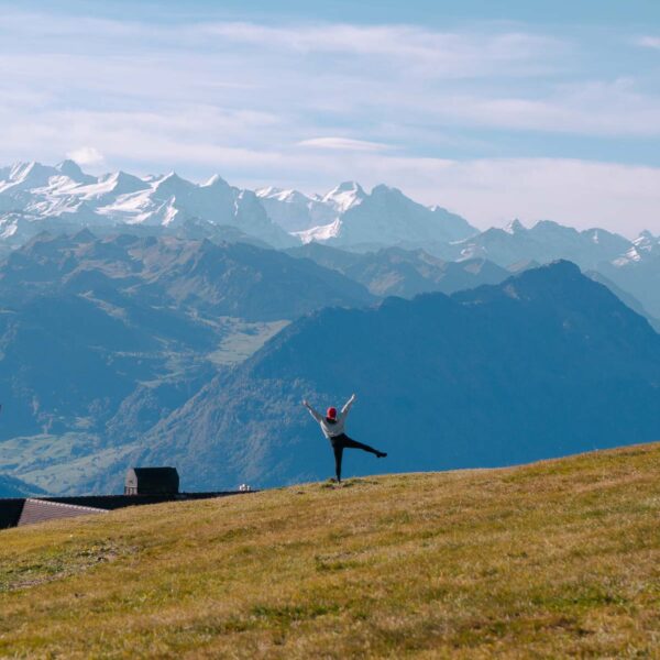 A hiker stretches out their arms on Rigi Kulm, embracing the panoramic Swiss Alps, easily reached with a Swiss Travel Pass