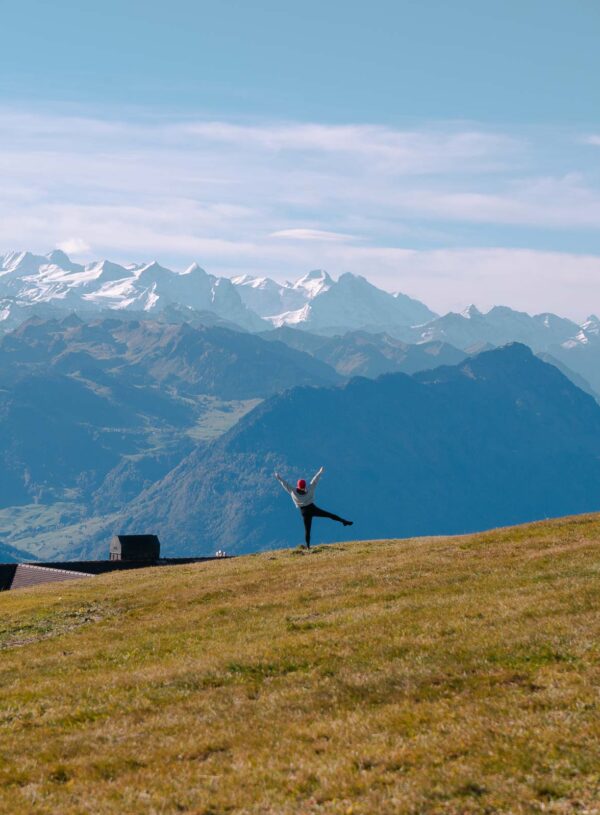 A hiker stretches out their arms on Rigi Kulm, embracing the panoramic Swiss Alps, easily reached with a Swiss Travel Pass