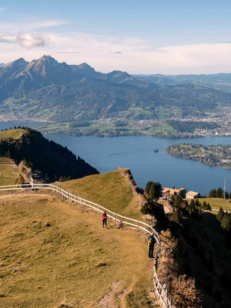 Hikers follow a trail along the ridge of Rigi Kulm, with the majestic Lake Lucerne unfolding in the valley below