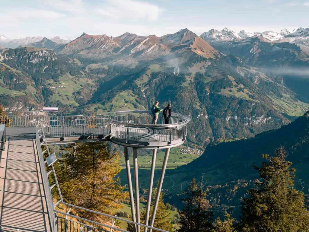 Visitors stand on the Stanserhorn's viewing platform, which extends over a stunning vista of mountain ranges and valleys