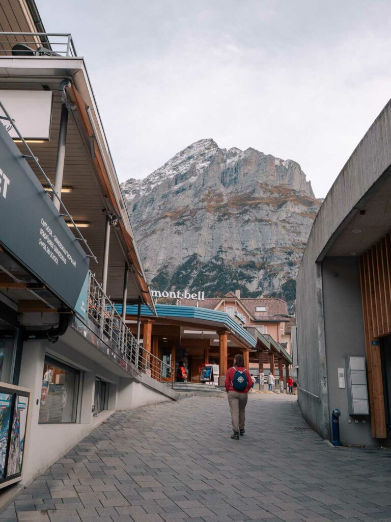 A lone traveller walks through the streets of Grindelwald with the imposing North Face of the Eiger looming in the background, an enchanting encounter on a ten day Switzerland itinerary