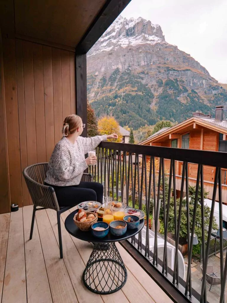 A guest savours a leisurely breakfast on the balcony of Bergwelt Design Hotel, overlooking the rustic charm of Grindelwald and the majestic Swiss Alps, a serene moment in a ten day Switzerland itinerary