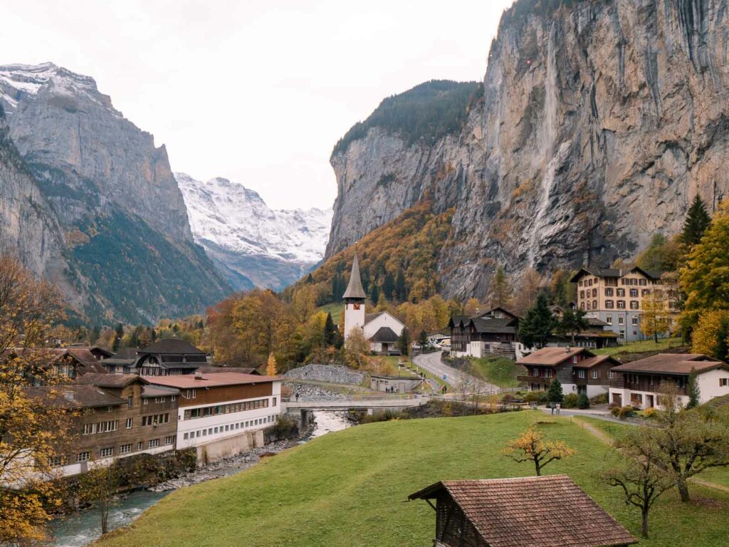 Lauterbrunnen village viewed from a train to Wengen, showcasing the church, traditional Swiss houses, and a backdrop of cliffs and mountains