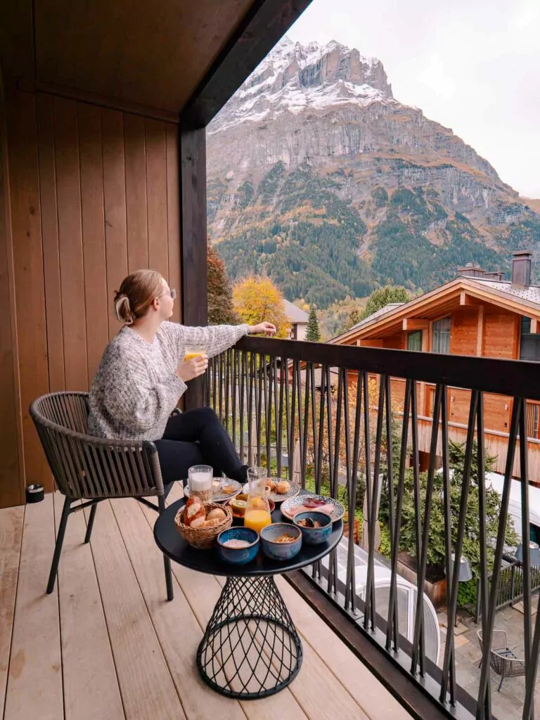 Alexx enjoying breakfast on a balcony at the Bergwelt Hotel in Grindelwald with a view of the snow-capped Swiss Alps in the background