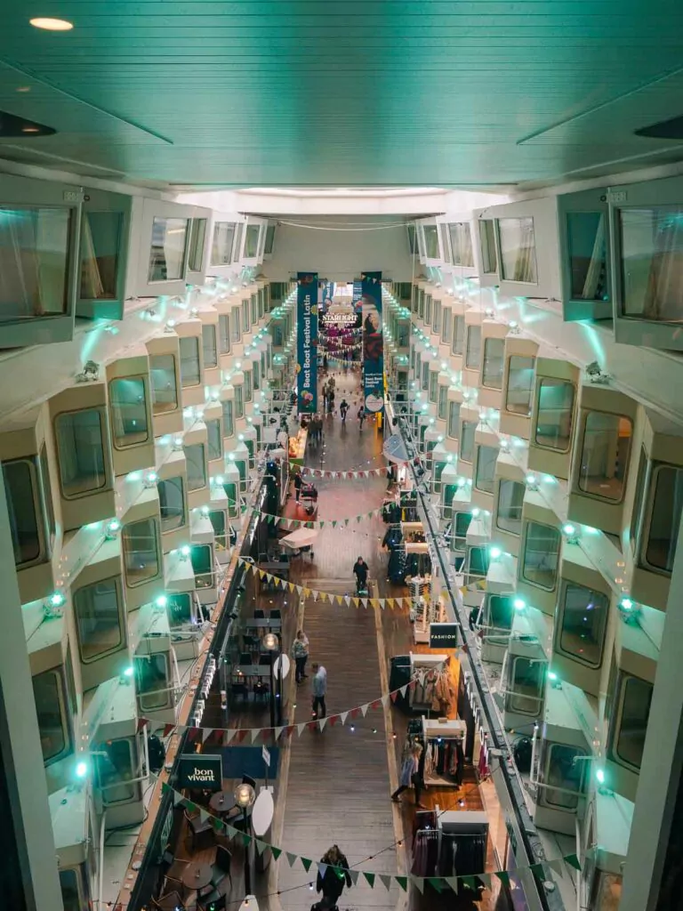 The grand promenade inside the Silja Symphony ferry, lined with rows of cabin windows overlooking a bustling walkway with shops and passengers, exemplifying a unique maritime shopping experience