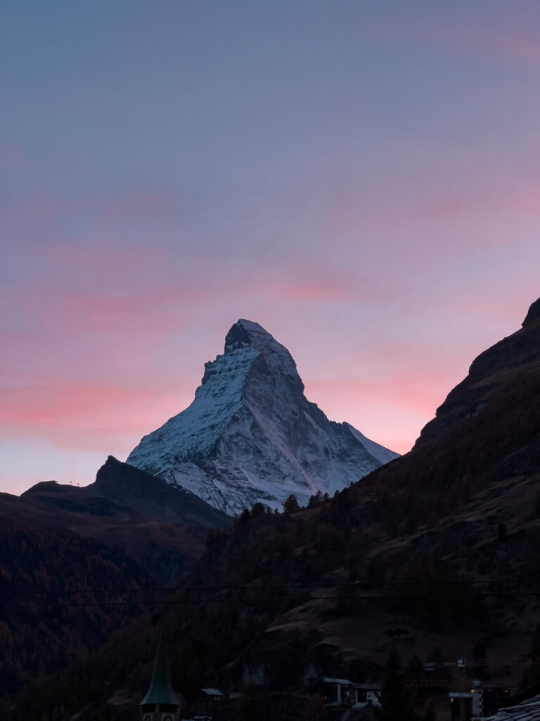 Matterhorn mountain illuminated by the early morning light with a pink and blue sky in the background, viewed from Hotel ZERMAMA