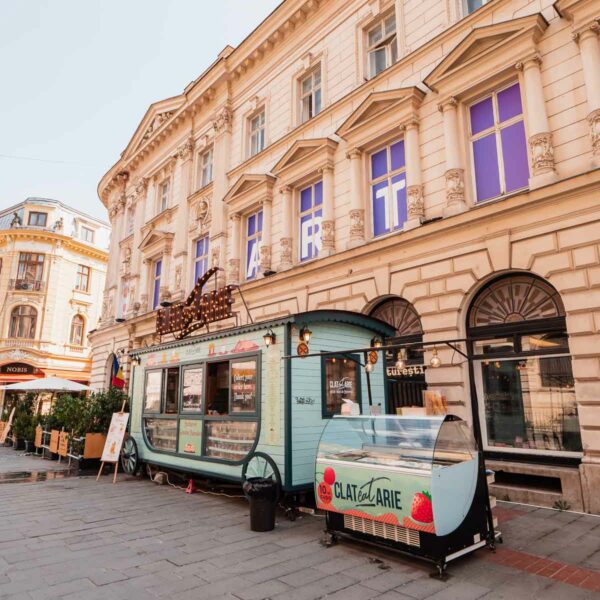 Vintage food truck turned ice cream stand on a cobblestone street in Bucharest, Romania, inviting passersby to indulge during their Balkans tour itinerary