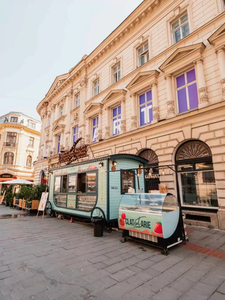 Vintage food truck turned ice cream stand on a cobblestone street in Bucharest, Romania, inviting passersby to indulge during their Balkans tour itinerary