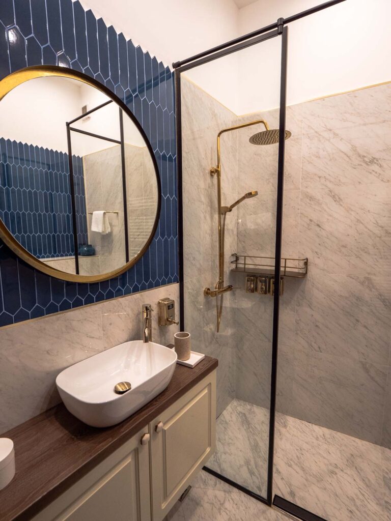 A modern bathroom with blue tiles and a walk-in shower, reflecting contemporary interior design in bucharest