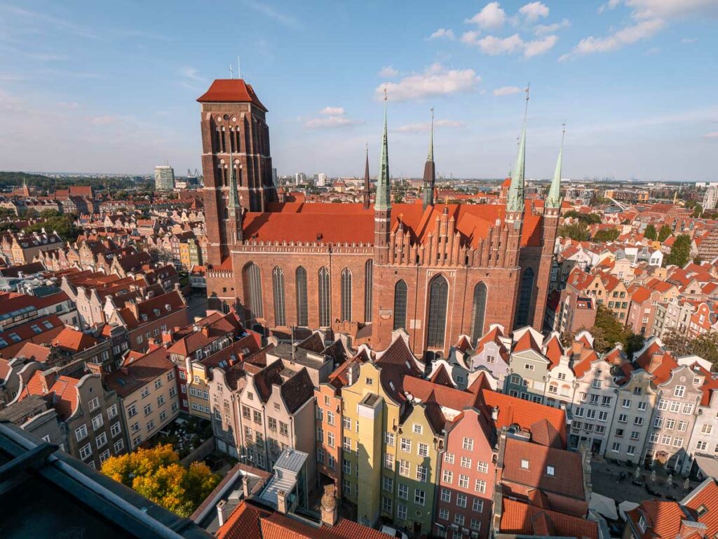 An aerial view of Gdansk Old Town with the red-brick St. Mary's Church standing tall among terracotta rooftops and colourful buildings, ideal for a Two Weeks in Poland travel itinerary