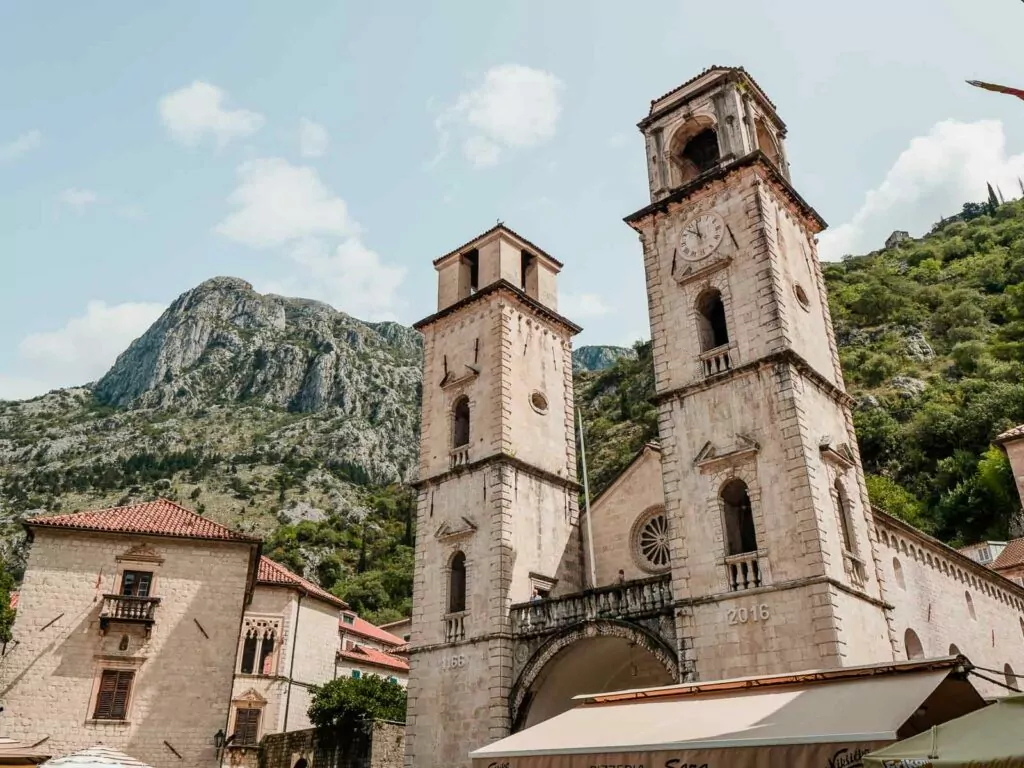 The ancient façade of the Cathedral of Saint Tryphon in Kotor, Montenegro, with its prominent twin towers against a mountain backdrop