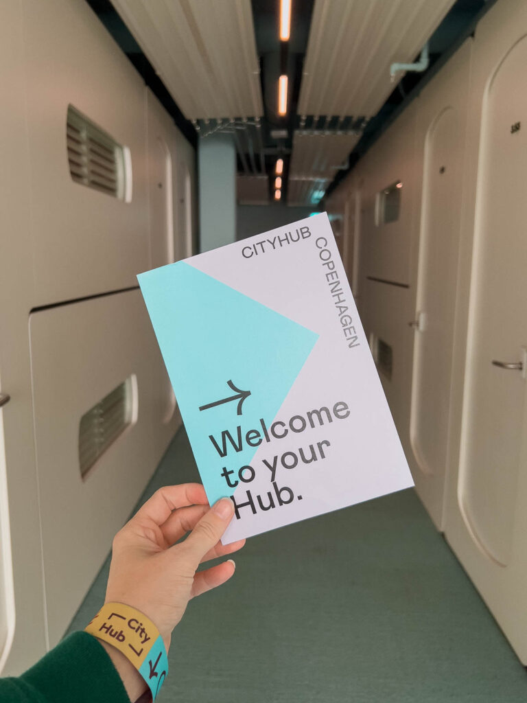 A hand holding a 'Welcome to your Hub' card in a corridor lined with doors at CityHub, one of the best hostels in Copenhagen for solo travellers