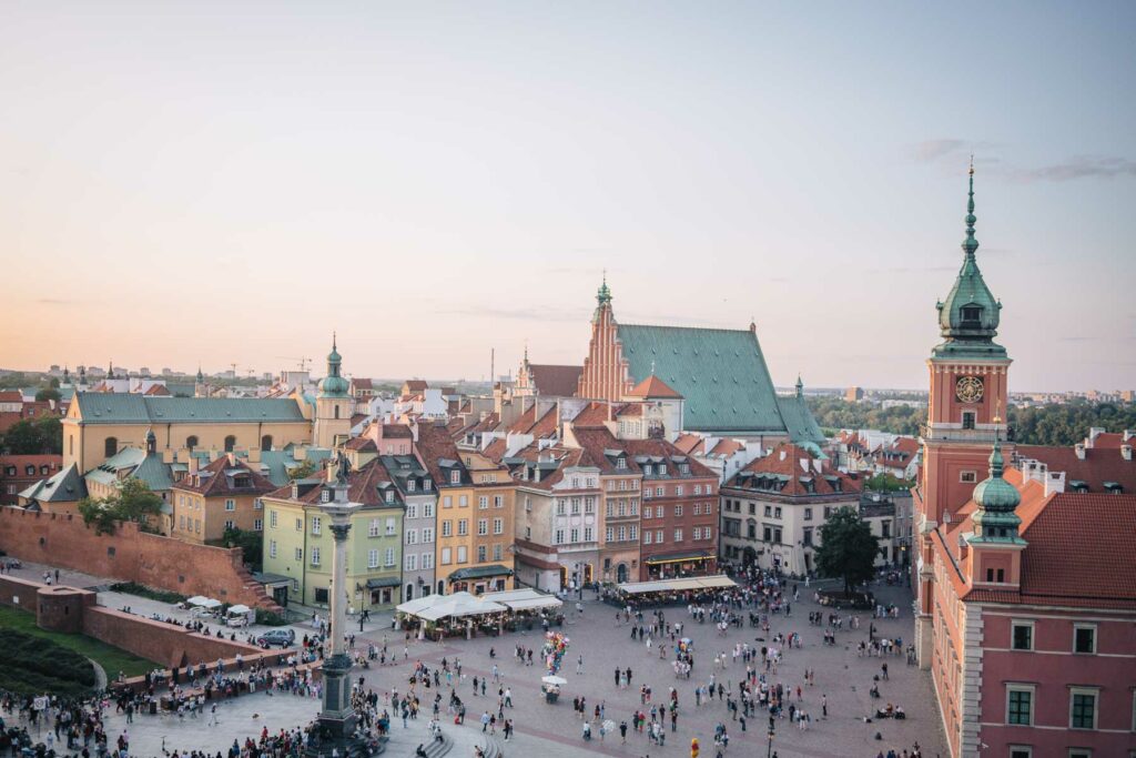An evening view from the tower viewing platform overlooking Warsaw's Old Town, capturing the historic rooftops and bustling squares in soft twilight, a picturesque stop on a two-week Poland itinerary