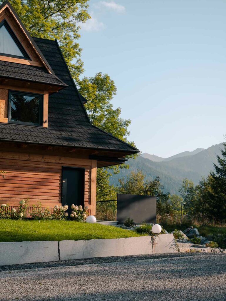 A traditional wooden villa in Zakopane, nestled in a tranquil setting with a mountainous backdrop, capturing the rustic charm of the region