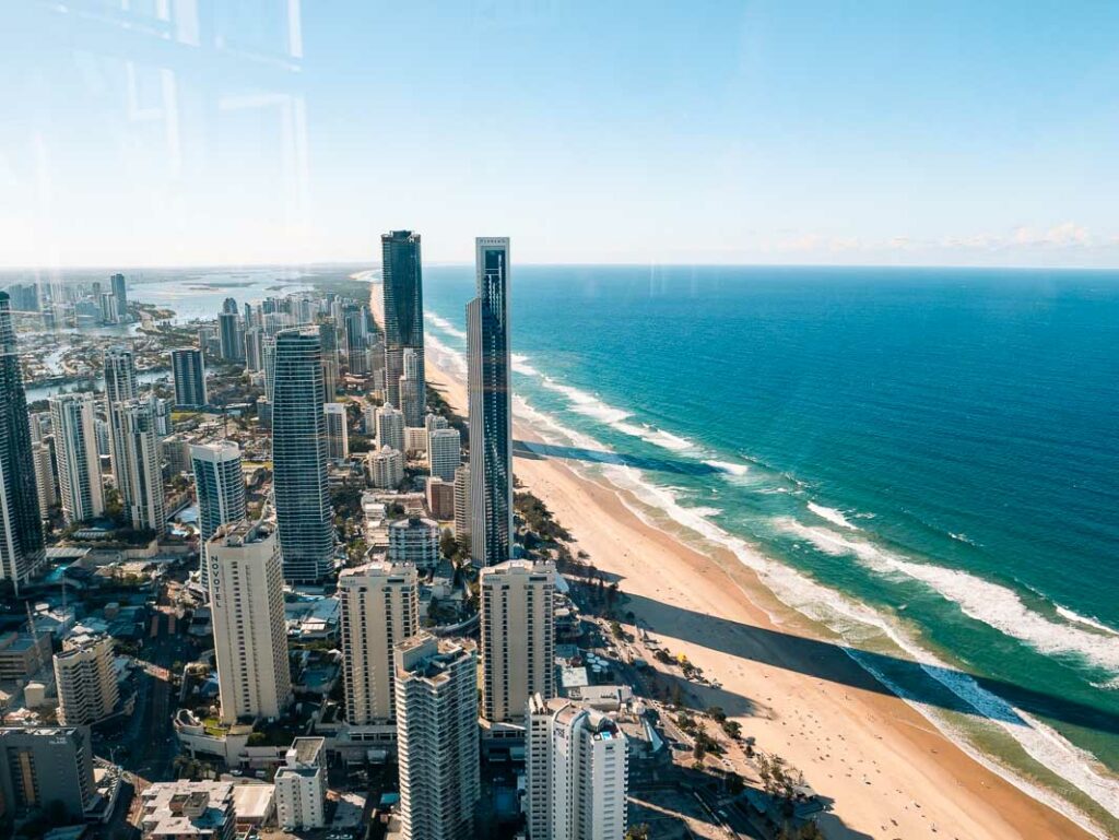 Stunning view of the Gold Coast from SkyPoint observation deck, showcasing towering skyscrapers along the expansive, golden sandy beach and the clear blue ocean stretching into the horizon