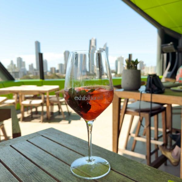 A refreshing Aperol Spritz on a rooftop restaurant table, offering a panoramic view of the bustling city skyline under a clear blue sky