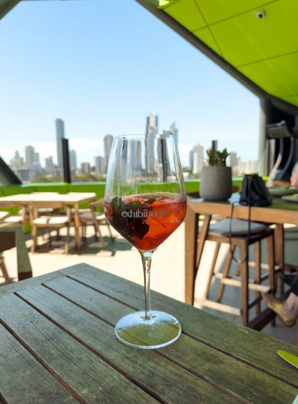 A refreshing Aperol Spritz on a rooftop restaurant table, offering a panoramic view of the bustling city skyline under a clear blue sky