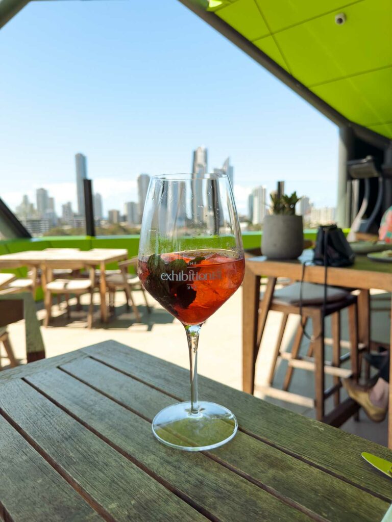 A refreshing Aperol Spritz on a rooftop restaurant table, offering a panoramic view of the bustling city skyline under a clear blue sky