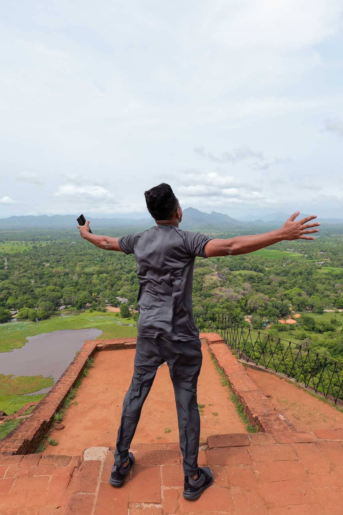 Our guide Rihas standing arms out in the wind on top of Sigiriya Rock in Sri Lanka