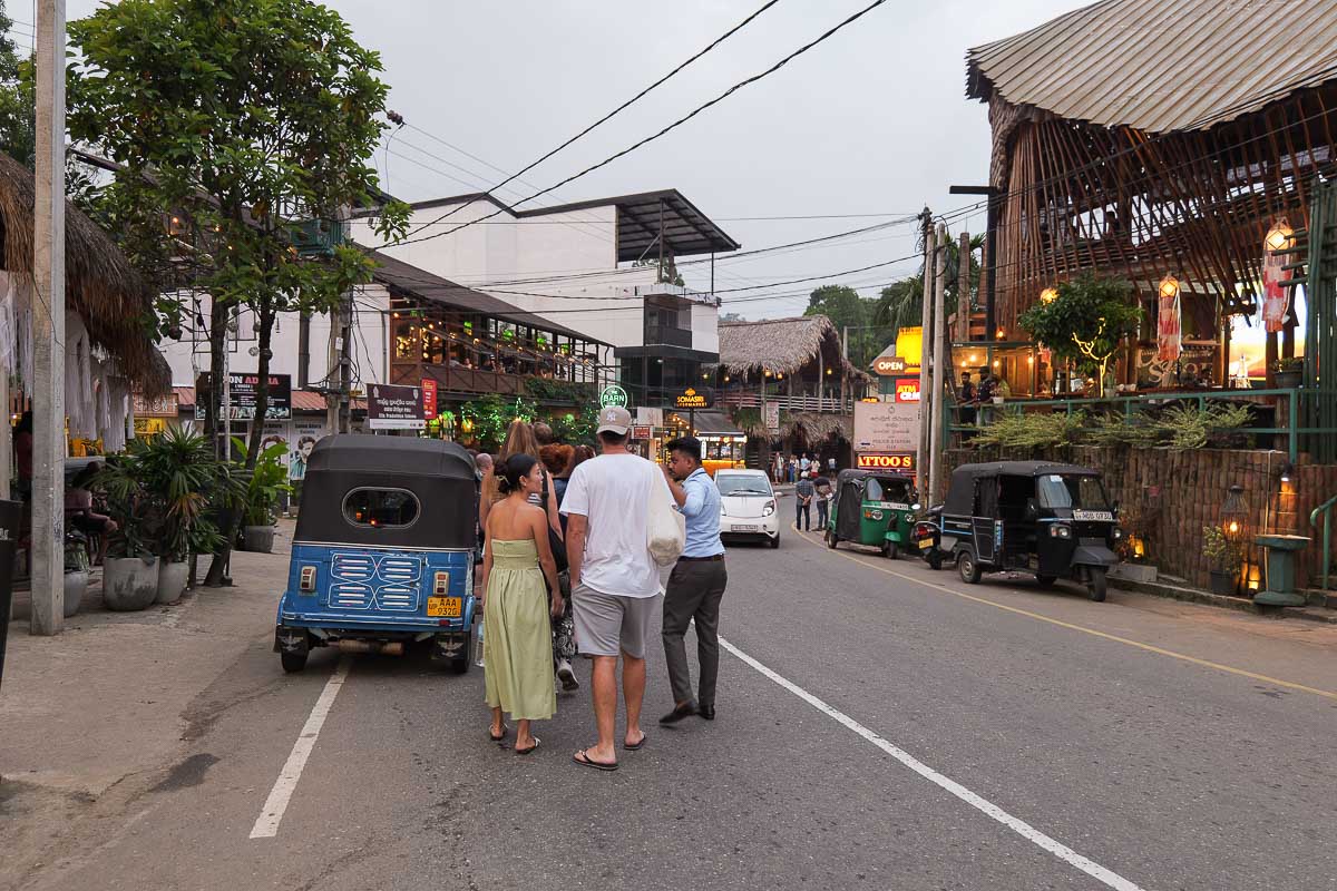 Tour group walking past tuk tuks on the main street in Ella, Sri Lanka