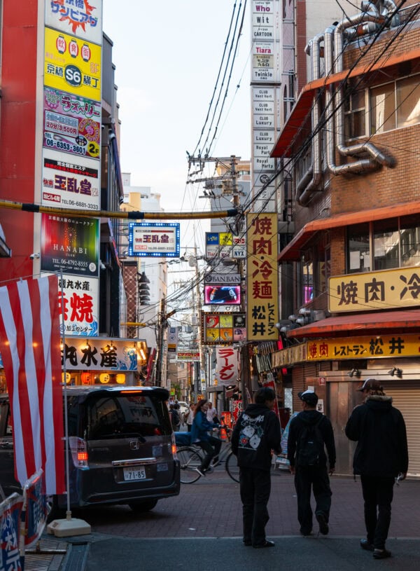 Busy street in Japan lined with shops and signs in Japanese.