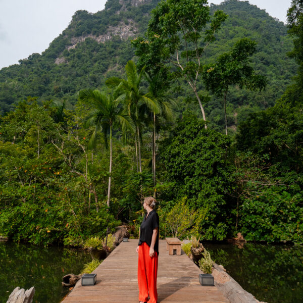 A wooden boardwalk surrounded by lush green mountains at Banjaran Hotsprings Retreat in Ipoh, a serene spot for solo travel in Malaysia