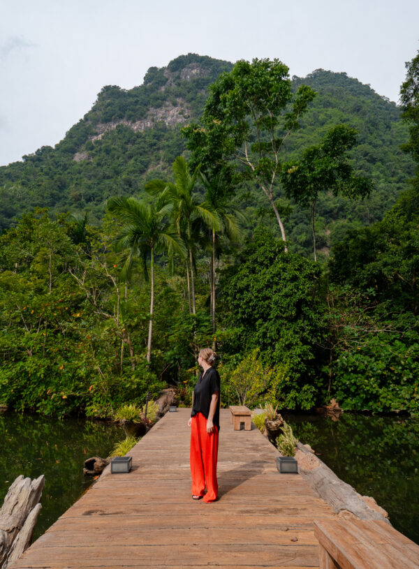 A wooden boardwalk surrounded by lush green mountains at Banjaran Hotsprings Retreat in Ipoh, a serene spot for solo travel in Malaysia