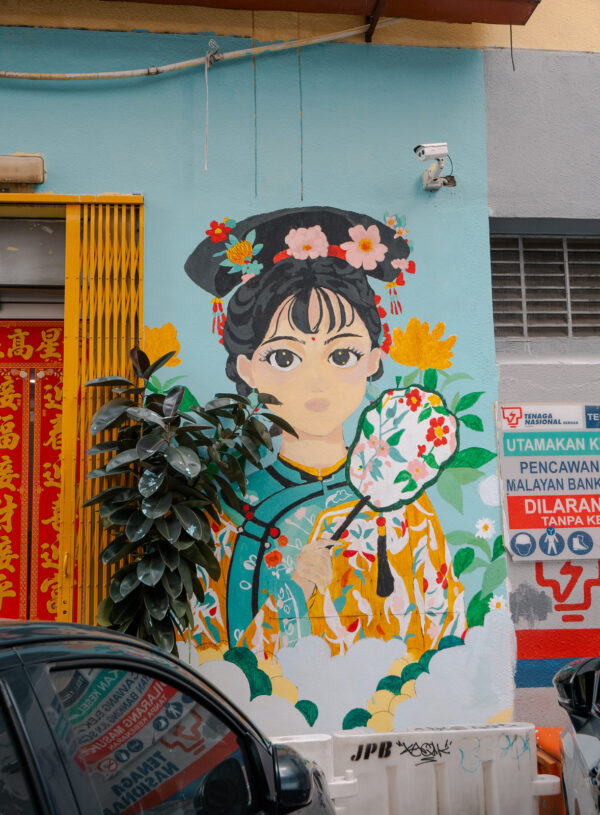 A charming mural of a woman in traditional dress on a street in Kuala Lumpur, adding to the city’s cultural appeal