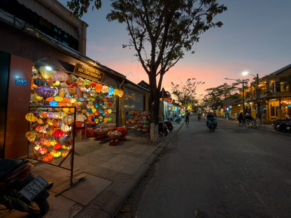 Colourful lanterns glowing over a Hoi An street at dusk