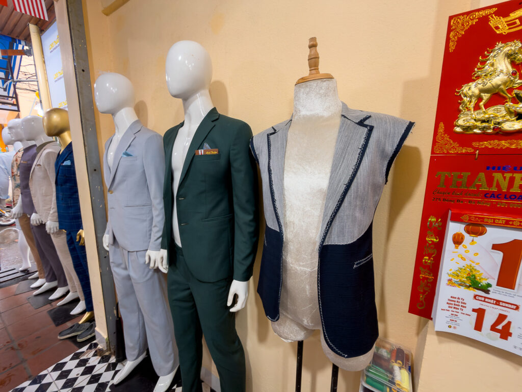 Tailored suits displayed on mannequins at Linh tailor in Hoi An