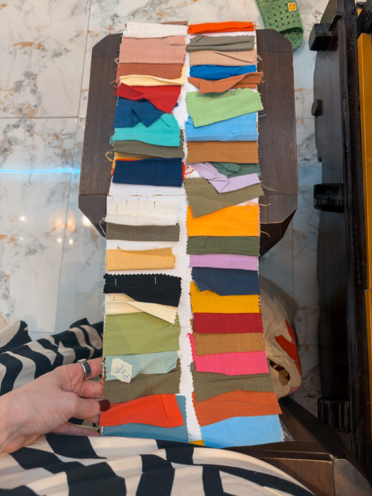 Hand holding a strip of colourful knit fabric swatches at a Hoi An tailor