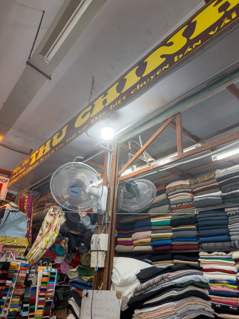 Fabric bolts stacked floor to ceiling at stall 51 Thu Chinh in the Hoi An cloth market