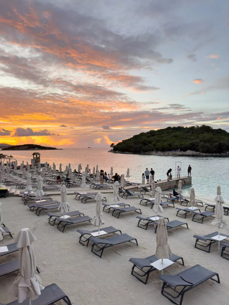 Identical sun loungers fill a beach at sunset in the Albanian Riviera, illustrating the standardisation of once-pristine coastline.