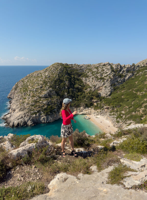 A solo female traveller in Albania enjoying the view over a secluded turquoise beach cove on a Riviera boat trip, showing off-the-beaten-path discoveries