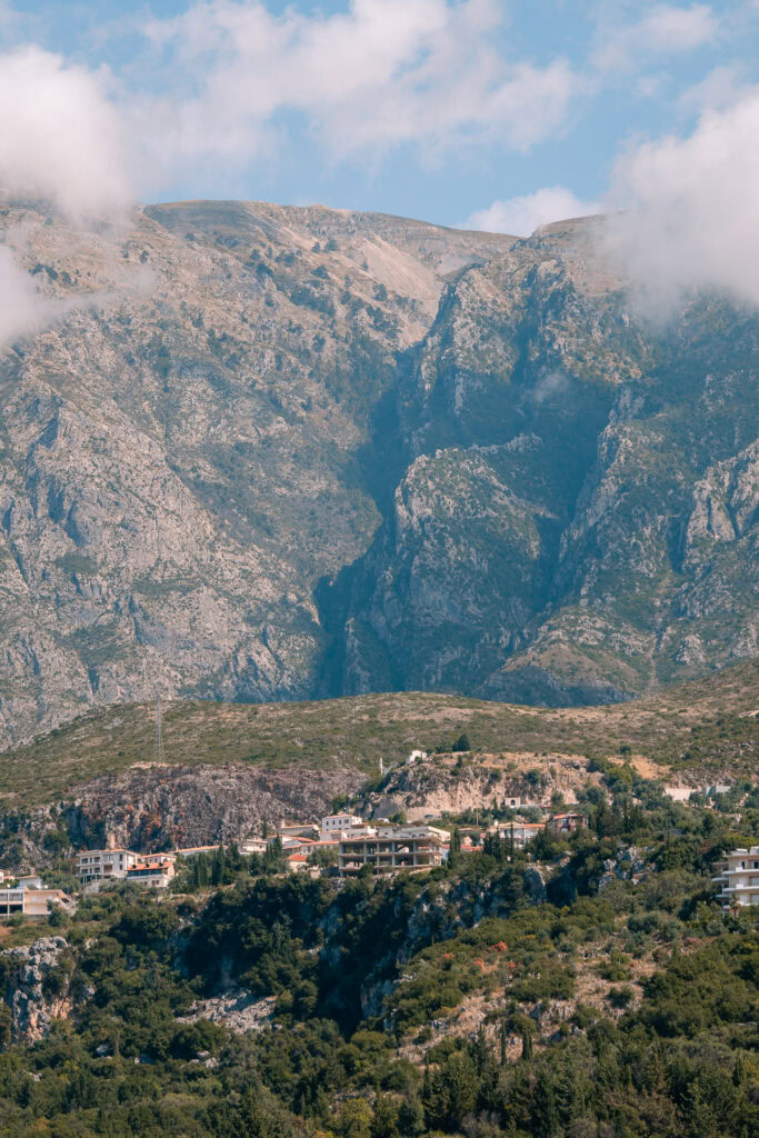 Mountain village of Dhermi nestled beneath dramatic mountains, traditional houses dotting green slopes.