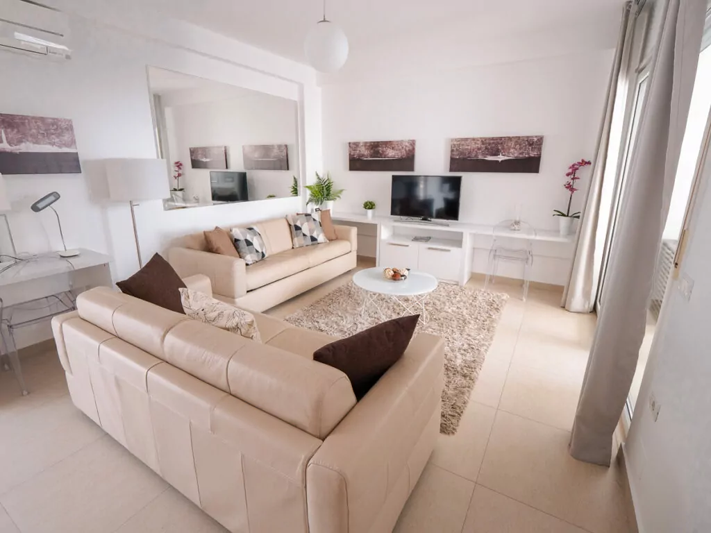 Spacious living room with cream L-shaped sofas and neutral decor, ideal for solo travellers seeking comfort in Albania.