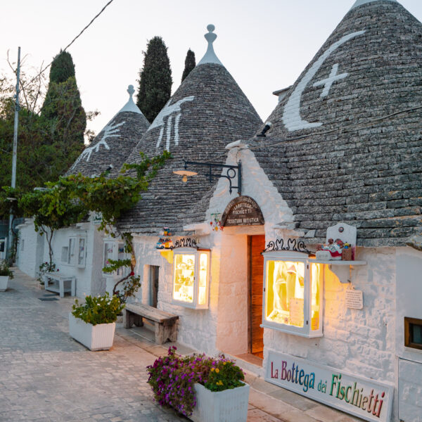 Illuminated trulli houses at dusk in Alberobello, an essential experience during two weeks in Puglia.