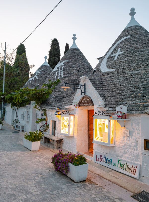 Illuminated trulli houses at dusk in Alberobello, an essential experience during two weeks in Puglia.