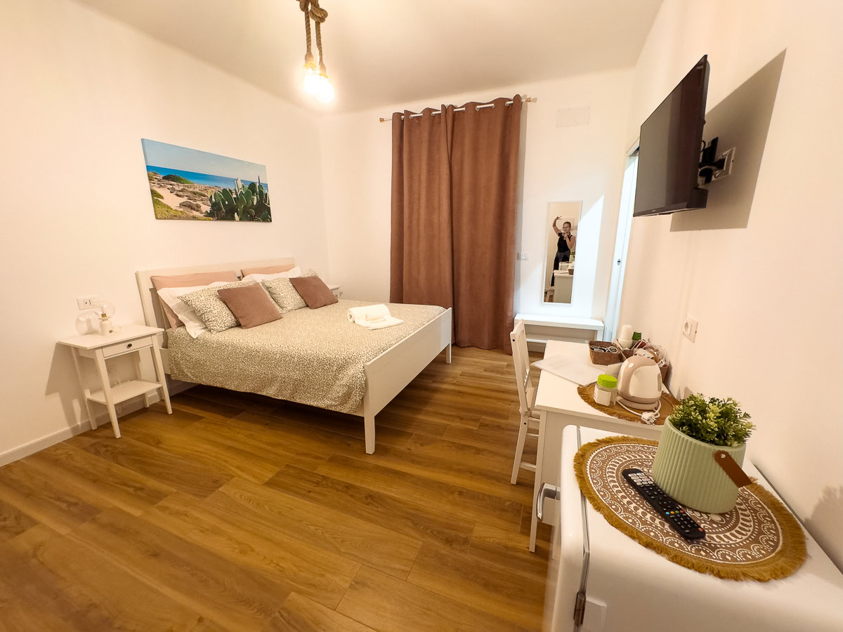 A bright, contemporary hotel room with wooden floors, white bedding, and coastal artwork.