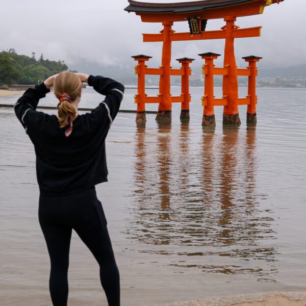 Tourist photographing iconic orange floating torii gate of Itsukushima Shrine at Miyajima Island