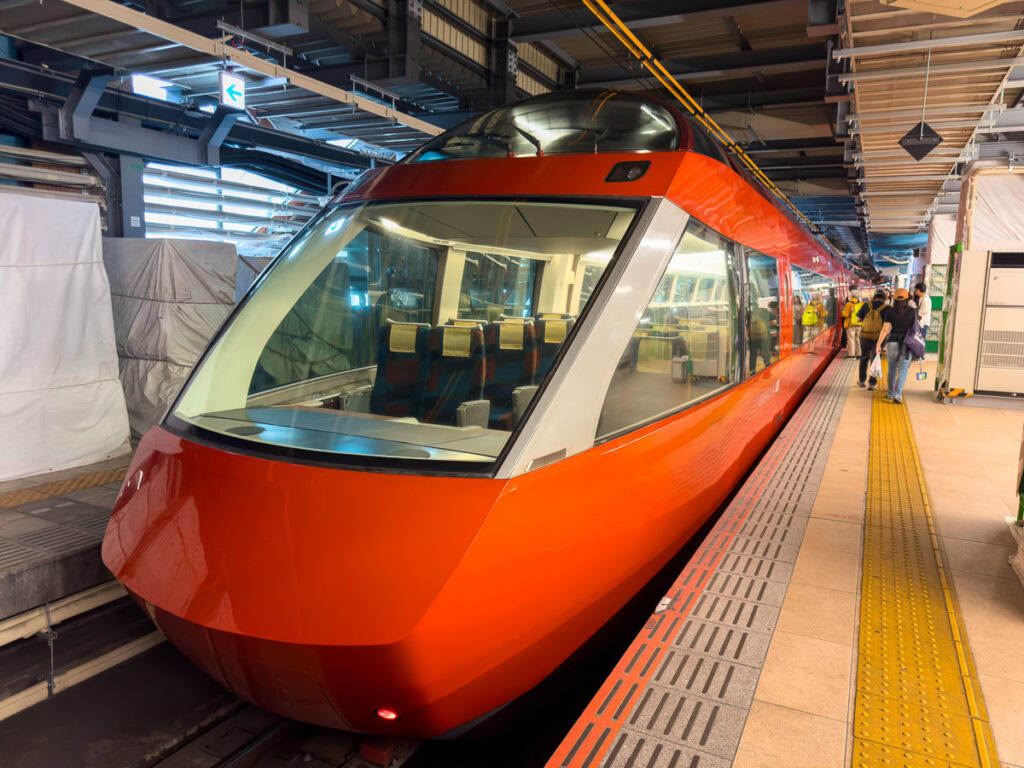 A sleek red and white limited express train waits at the platform, representing Japan's efficient railway system
