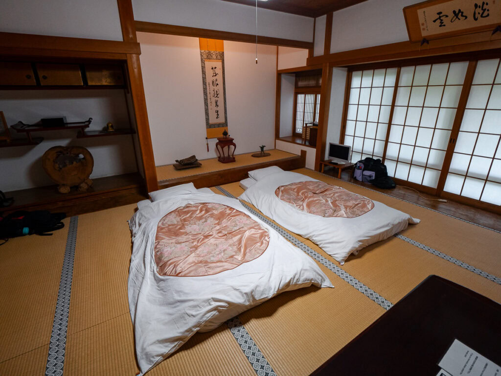 Traditional Japanese temple accommodation at Koyasan with futon bedding laid out on tatami mats in wooden room with sliding paper doors