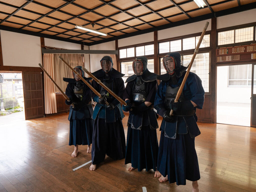 Group of people learning Japanese swordsmanship in authentic dojo setting in Kyoto with wooden floors and paper screens