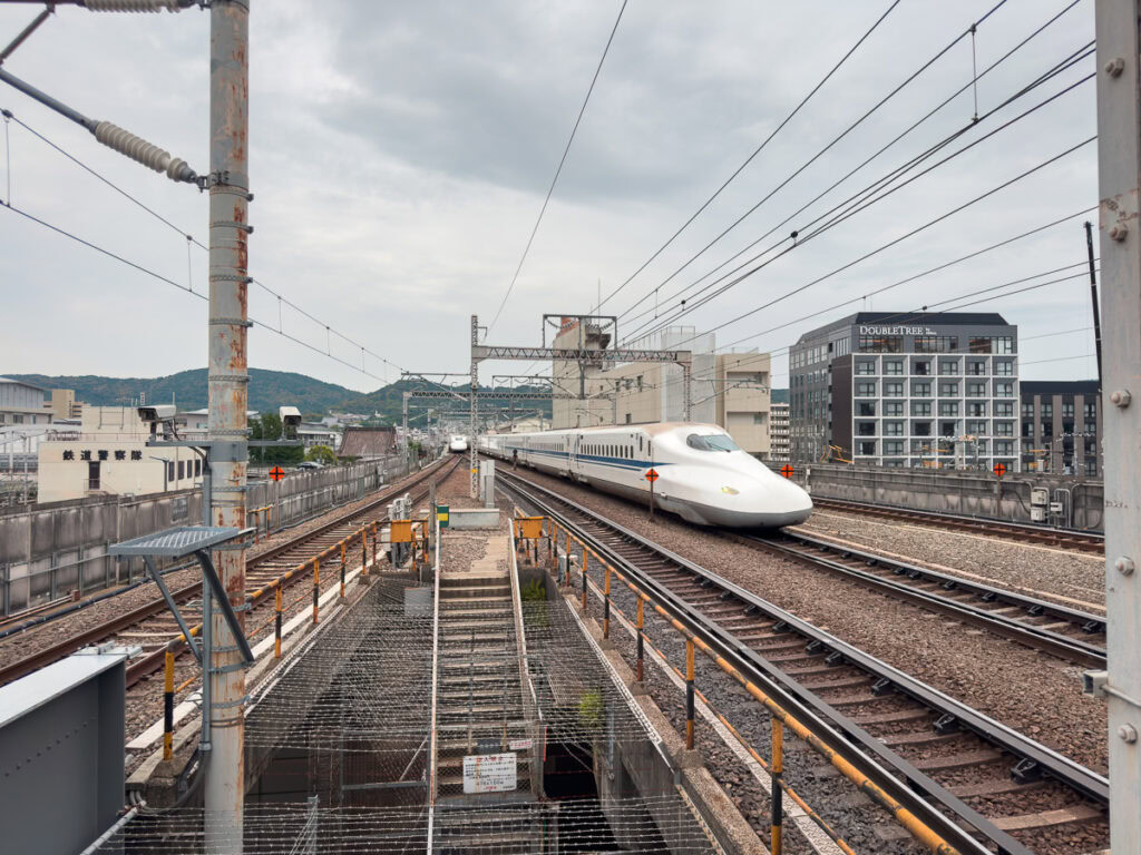 Railway tracks stretch into the distance in Nagano with power lines overhead and mountains visible in the background, showcasing Japan's extensive rail network