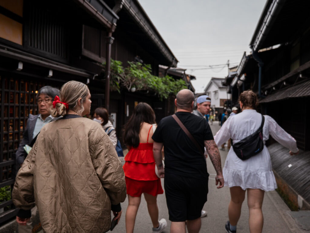 Tourists walking along historic preserved street in Takayama with wooden buildings and mountain town atmosphere
