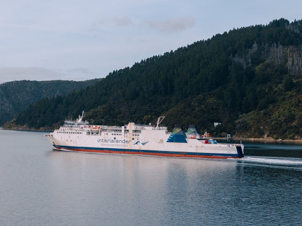 The Interislander ferry sailing on calm water with steep forested hills of the Marlborough Sounds on both sides