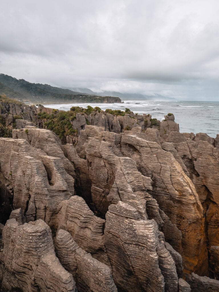 Layered limestone Pancake Rocks at Punakaiki on the West Coast with the Tasman Sea and foggy mountains in the background