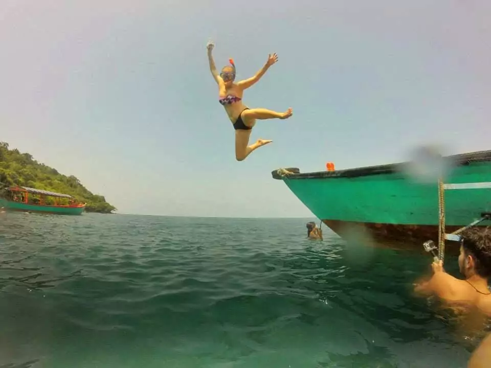 Alexx jumping off a boat into turquoise water in Cambodia on her first G Adventures tour in 2015